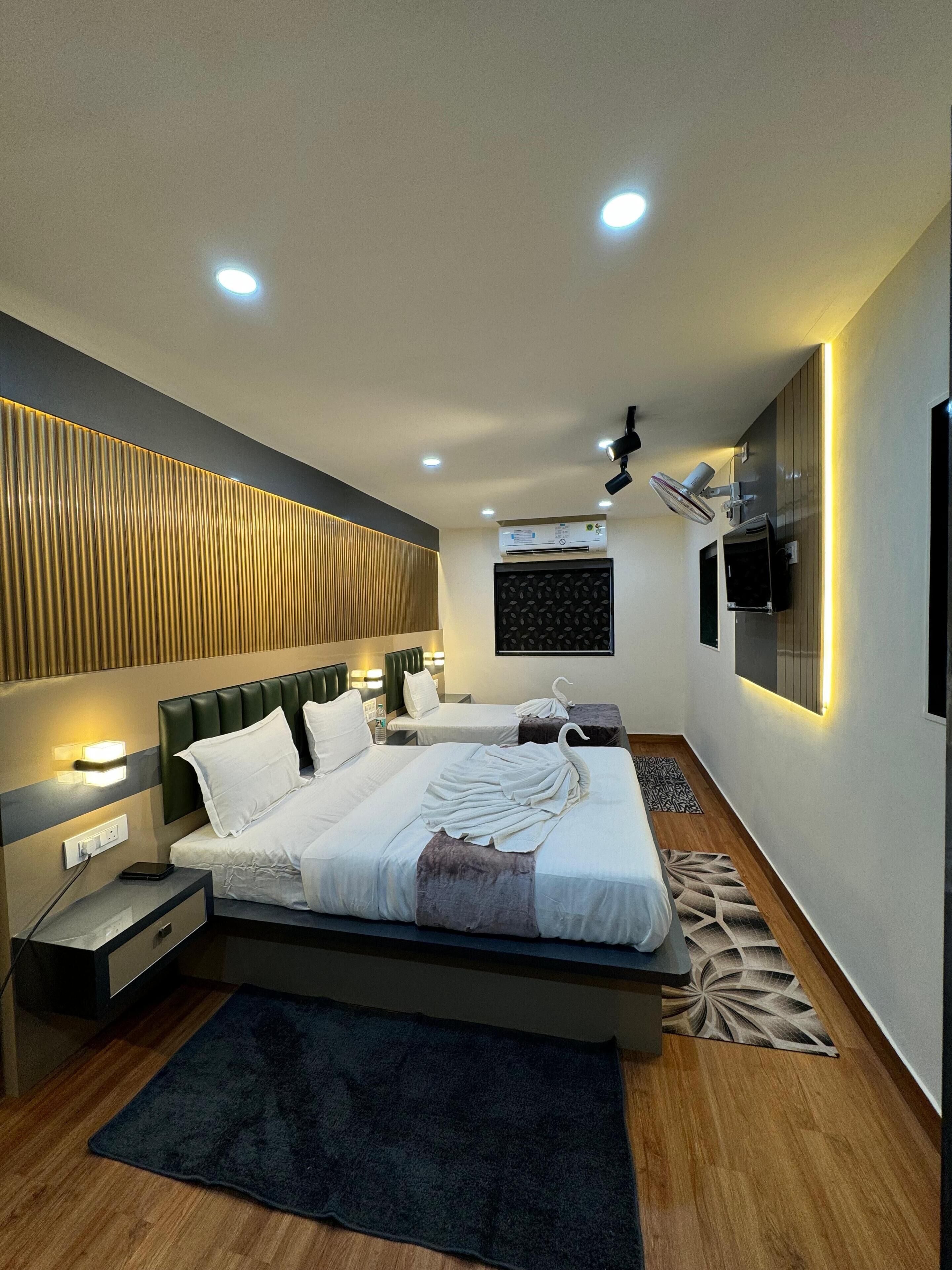 A modern hotel room with a large bed, bedside tables, a TV, and an air conditioning unit.