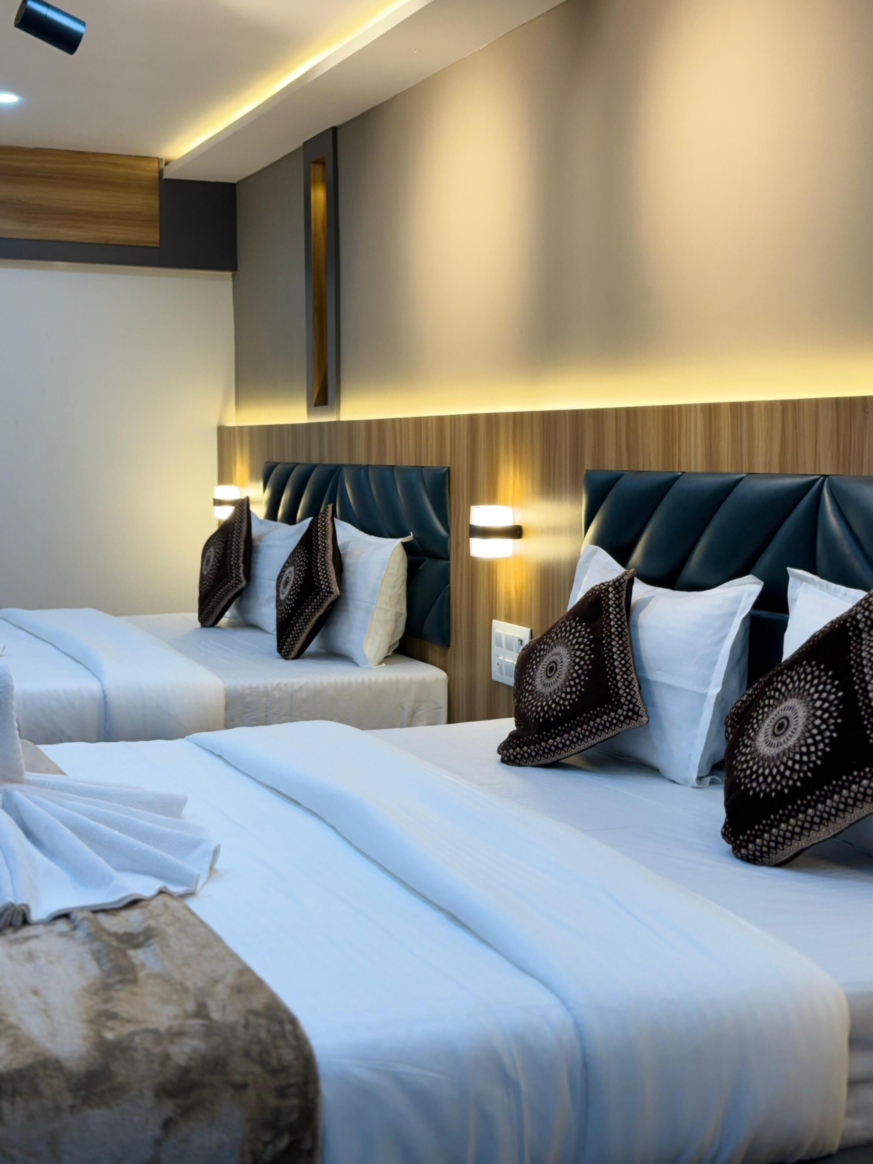 A hotel room with two beds, each with a headboard, bedside lamps, and decorative pillows.