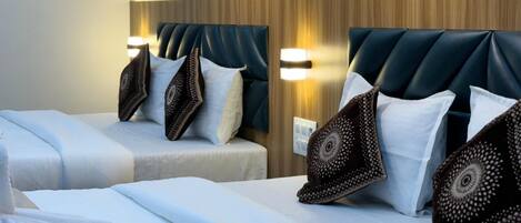A hotel room with two beds, each with a headboard, bedside lamps, and decorative pillows.