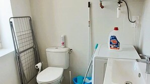 Une petite salle de bain comprenant des toilettes, un lavabo et un chauffe-eau fixé au mur.