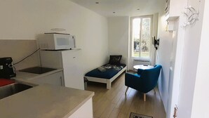 Une pièce compacte comprenant un coin cuisine, un lit, une petite table et une chaise.