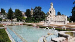 Une fontaine ornée d’une statue, entourée d’un bassin et de marches.