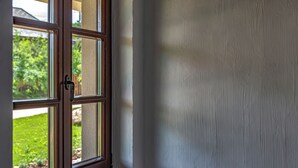 A window with a view of a green lawn and a wooden deck.