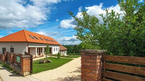 A house with a red roof, a gravel driveway, and a wooden fence.