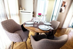 A dining area with a round wooden table set for four, surrounded by patterned armchairs. - Lux central 1,5 bedroom apartment (Berlin)