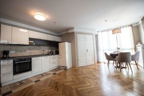 A modern kitchen with white cabinets, a built-in oven, and a dining area with a table and chairs. - Lux central 1,5 bedroom apartment (Berlin)
