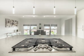A modern kitchen with a central gas stove, pendant lighting, and a view of the outdoors. - Ocean Drive Splendor Awaits (Corpus Christi)