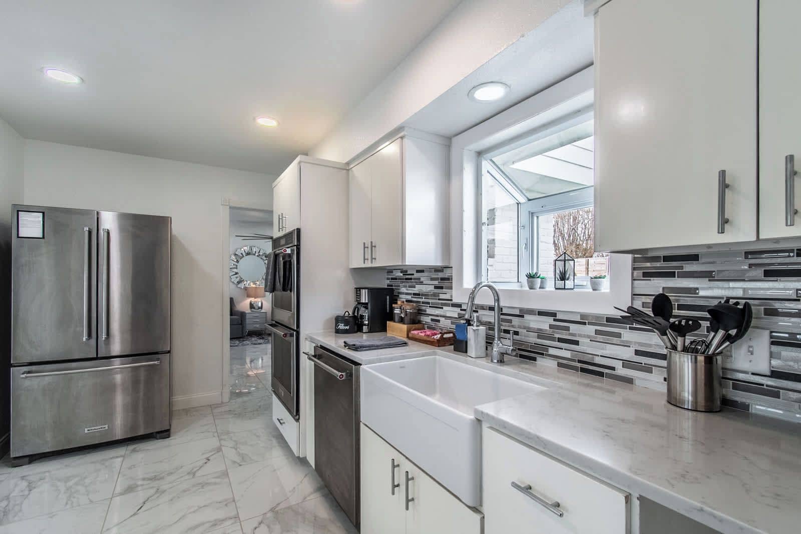 A modern kitchen with stainless steel appliances, a large sink, and a window above the countertop.