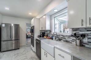 A modern kitchen with stainless steel appliances, a large sink, and a window above the countertop. - Ocean Drive Splendor Awaits (Corpus Christi)