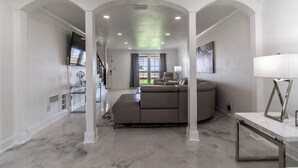 A spacious living room with a large sectional sofa, a flat-screen TV, and a dining area with a table and chairs. - Ocean Drive Splendor Awaits (Corpus Christi)