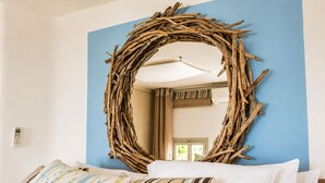 Une pièce décorée d’un élément mural circulaire en fibres tressées, un lit avec des coussins à rayures et une porte visible au fond.