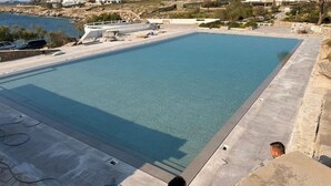 Une grande piscine rectangulaire entourée d’une terrasse en béton.