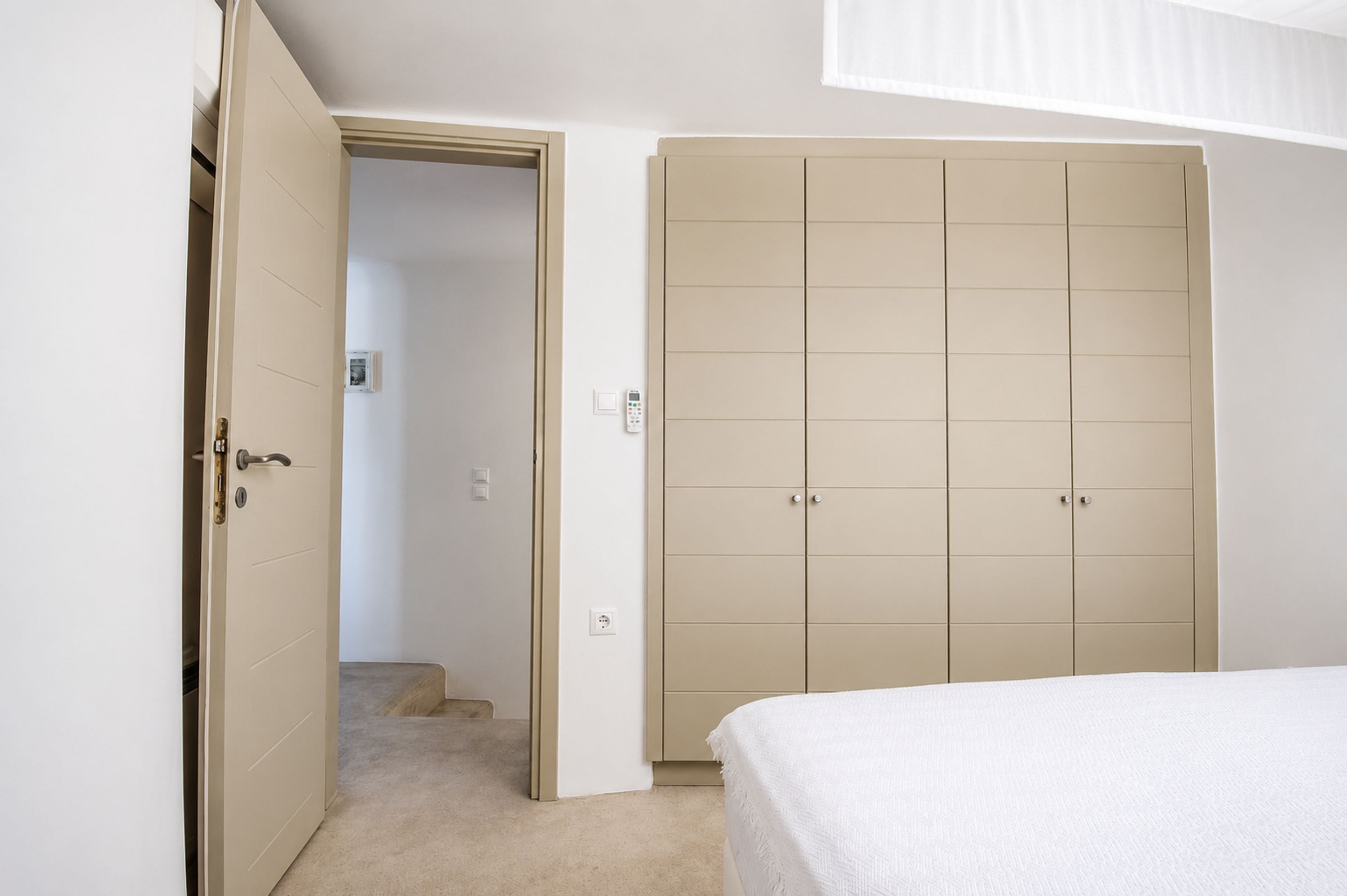 A bedroom with a bed, a wardrobe, and a door leading to another room.