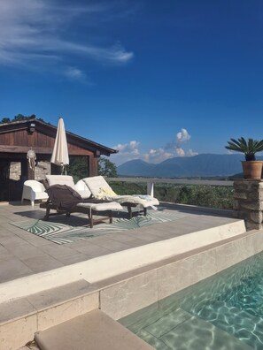 A poolside area with lounge chairs, a covered seating area, and a view of mountains. - Accommodation in the complete relaxation of nature, minimal with elegant details... (Faicchio)