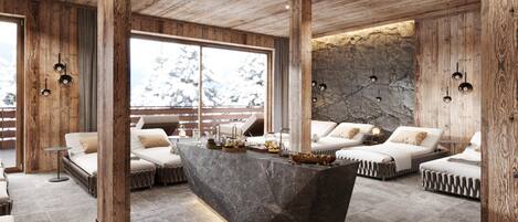 A modern interior with a central island, wooden beams, stone walls, and a view of snow-covered trees.