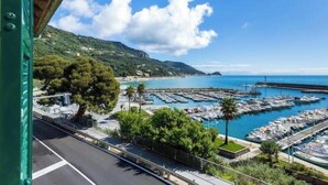 Un puerto deportivo con barcos amarrados, un cielo azul despejado y un paisaje montañoso al fondo.