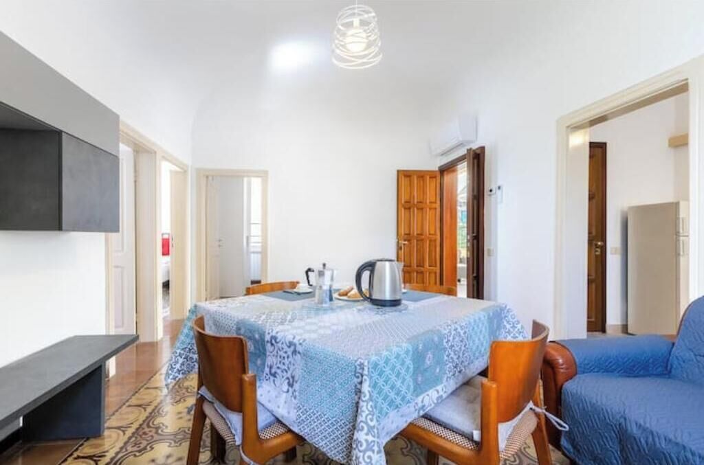 Un coin repas avec une table dressée pour deux personnes, un banc et un canapé bleu.