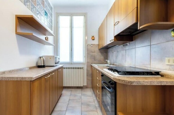 A compact kitchen with wooden cabinets, a built-in stove, and a window.