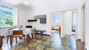 Un comedor con mesa y sillas, un banco, una lámpara colgante y vistas al exterior.