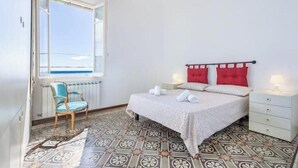 Un dormitorio con cama, una silla, una mesita de noche y una ventana con vistas.