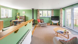 Ein Wohnzimmer mit einer Couch, einem Couchtisch, einem Fernseher und einem Essbereich mit Stühlen und einem Tisch.