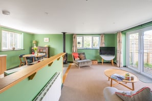 A living room with a sofa, a coffee table, a TV, and a dining area with chairs and a table. - Moor View, Reepham, Norfolk (Reepham)