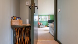 Ein Flur, der zu einem Zimmer mit einem Bett, einem Fernseher und einem Vorhangfenster führt.