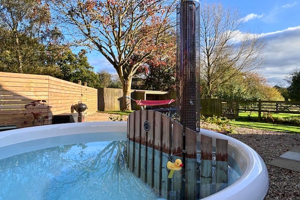 A hot tub with a wooden fence, a metal structure, and a tree with autumn leaves. - Moor View, Reepham, Norfolk (Reepham)