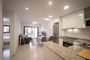 Eine moderne Küche mit Granit Arbeitsplatten, Edelstahlgeräten und einem Essbereich mit Tisch und Stühlen.