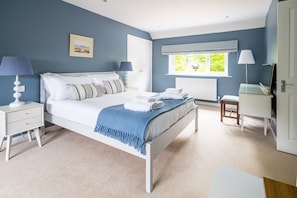 A bedroom with a bed, bedside tables, a dresser, a window with blinds, and a radiator. - Manor Farm Lodge, Brancaster, Norfolk (Brancaster)