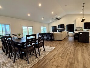 A spacious living area with a dining table, chairs, a sofa, and a kitchen area with a TV and fireplace. - Lakeview Canyon at Bear Lake (Garden City)