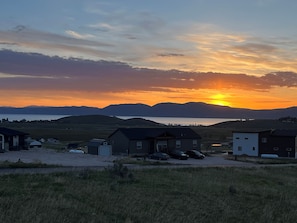 A residential area with houses, a body of water, and mountains in the background.