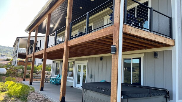 Une maison à deux étages dotée d’un balcon, d’un espace salon extérieur et d’un jacuzzi.