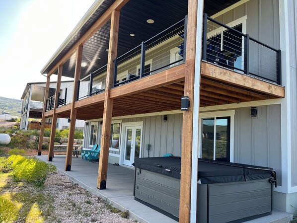 A two-story house with a balcony, outdoor seating, and a hot tub.
