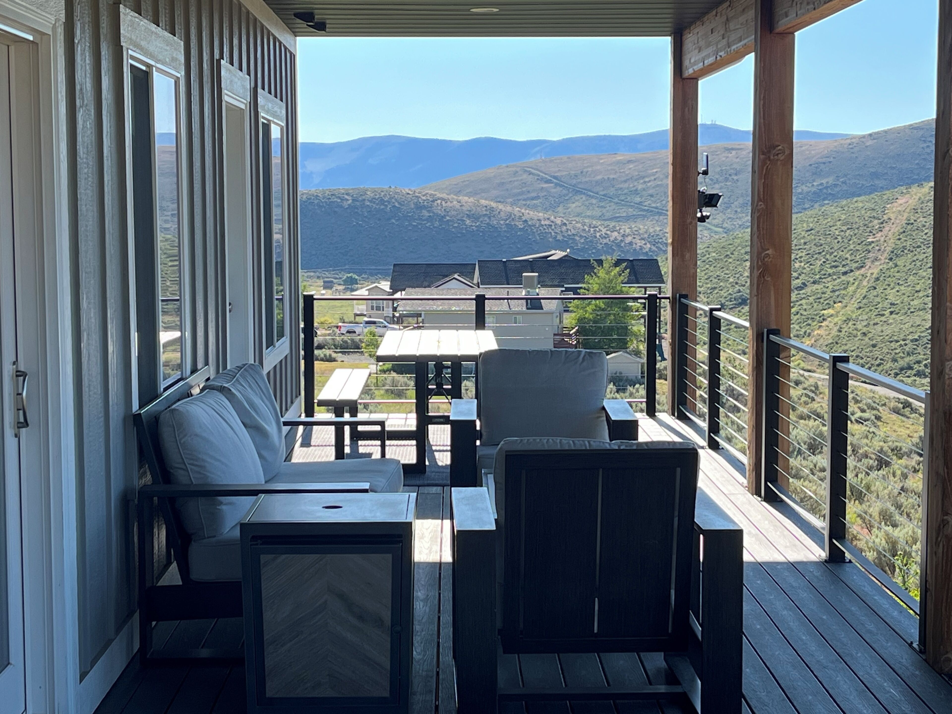 A covered outdoor seating area with a view of a hilly landscape.