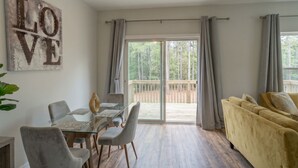 Ett modernt vardagsrum med ett glasbord, en soffa och en skjutdörr i glas som leder ut till en terrass.