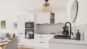 Eine moderne Küche mit weißen Schränken, einem Einbauofen, einer Mikrowelle, einer Kaffeemaschine und einem Spülbecken.