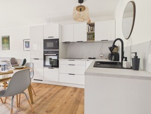 A modern kitchen with white cabinetry, a built-in oven, a microwave, a coffee maker, and a sink. - 300m from beach, apt for 3 (Pornichet)