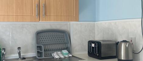 A kitchen with wooden cabinets, a stainless steel sink, a toaster, a kettle, and a microwave.