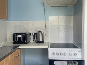 Eine Küchenzeile mit einem schwarzen Toaster, einem Wasserkocher und einem weißen Herd.