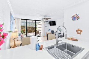 Eine moderne Küche mit Spüle aus Edelstahl, Deckenventilator und Essbereich mit Tisch und Stühlen.