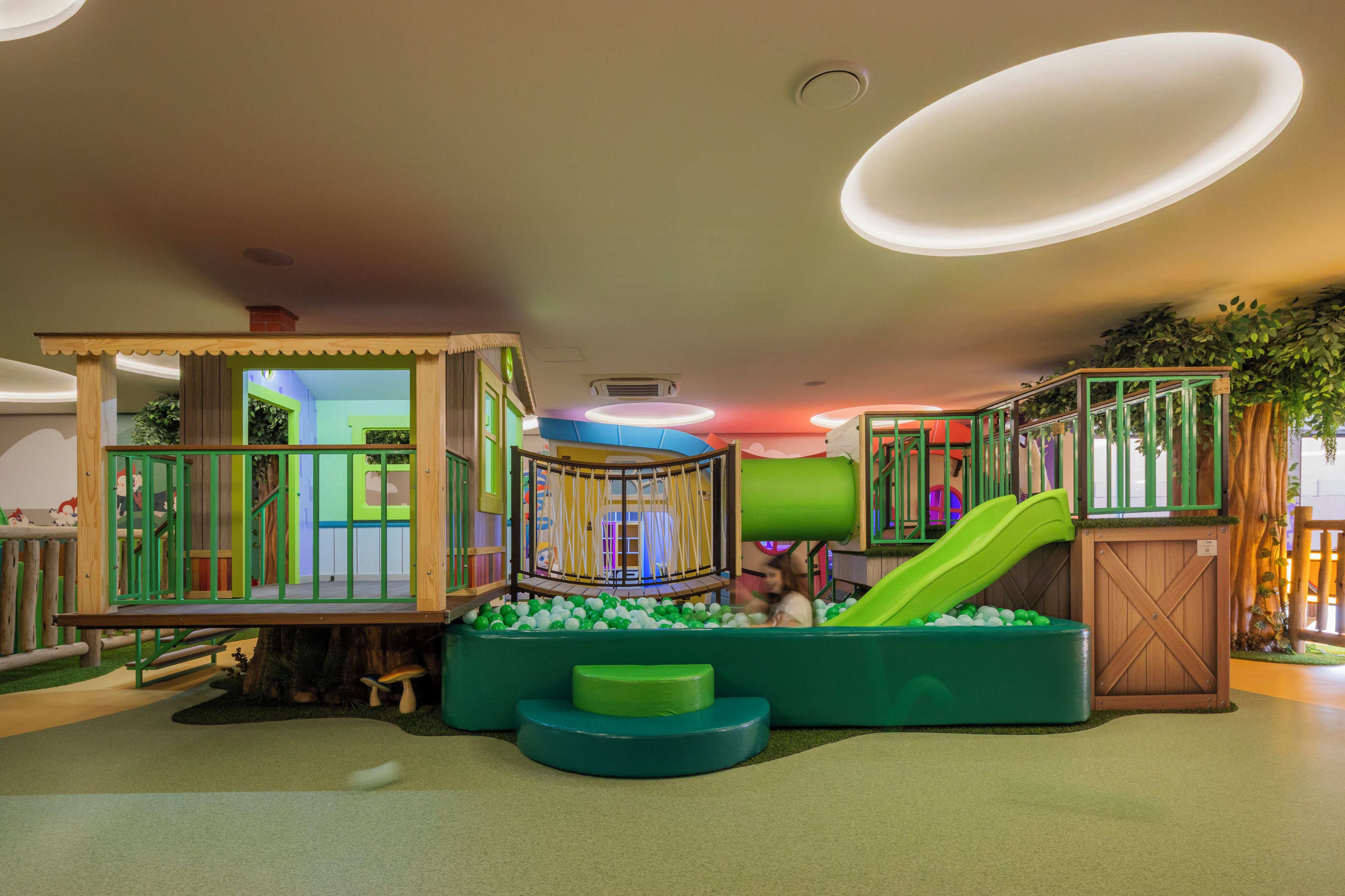 Un espace de jeux pour enfants avec un toboggan, des structures d’escalade et une piscine à balles.
