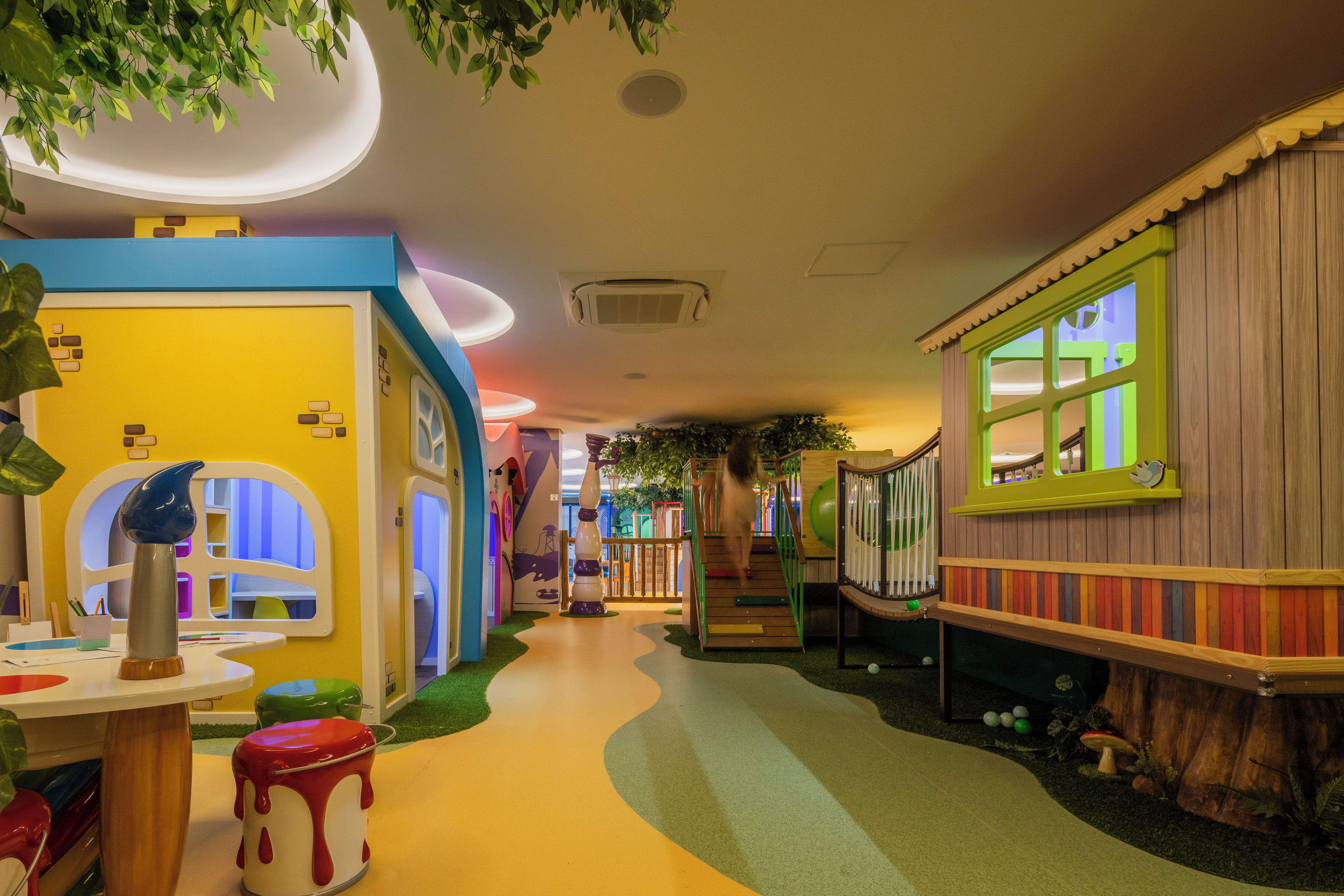Un área de juegos infantiles con paredes coloridas, un sendero sinuoso y diversas estructuras de juego.