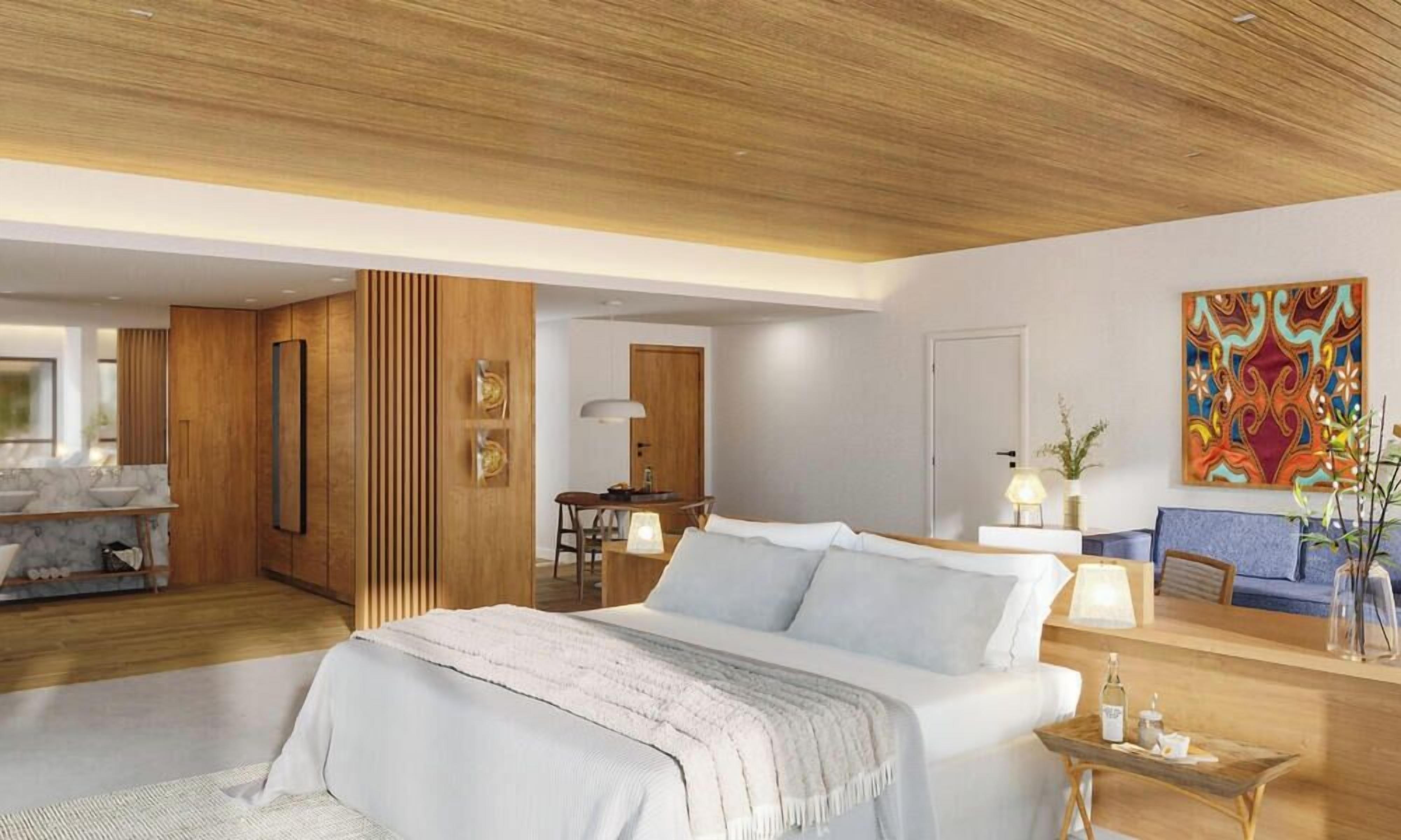 A modern hotel room with a large bed, a desk, a sofa, and a dining area.