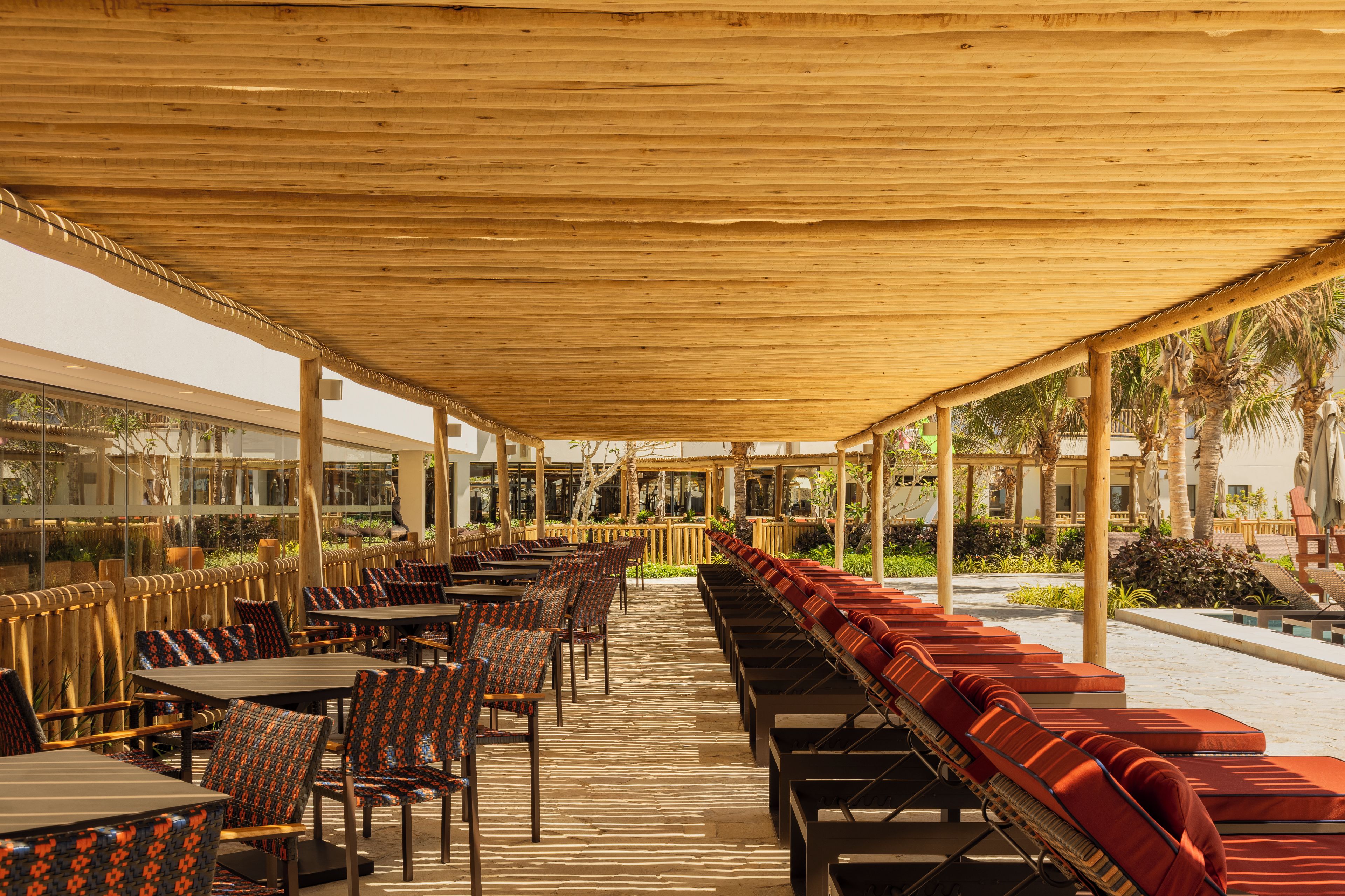 An outdoor seating area with tables and chairs, a covered walkway, and a view of the surrounding landscape.
