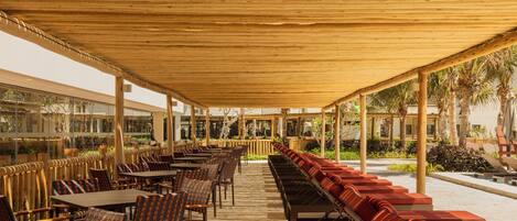 An outdoor seating area with tables and chairs, a covered walkway, and a view of the surrounding landscape.