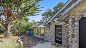 A house with a stone facade, a garage door, and a tree in the yard. - New Listing--A Woodland Escape--Call for Monthly Rates (Cambria)