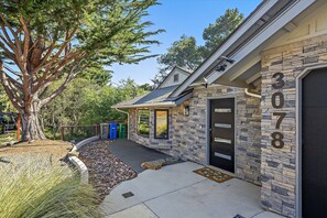 A house with a stone facade, a garage door, and a tree in the yard. - New Listing--A Woodland Escape--Call for Monthly Rates (Cambria)