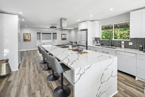 A modern kitchen with a marble island, bar stools, and a large window. - New Listing--A Woodland Escape--Call for Monthly Rates (Cambria)