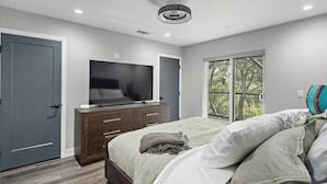 A bedroom with a bed, a TV, a dresser, and a window with a view. - New Listing--A Woodland Escape--Call for Monthly Rates (Cambria)